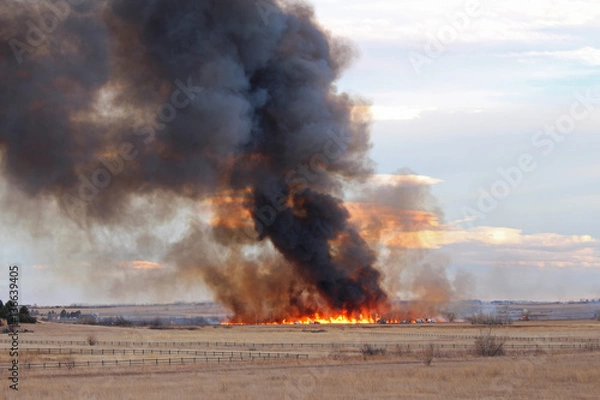 Fototapeta A wildfire in Colorado produces a plume of black smoke rising into the sky.