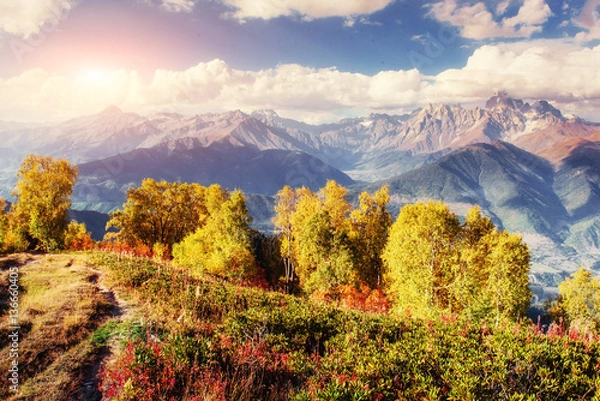 Fototapeta Autumn landscape and snow-capped mountain peaks. View of the mou