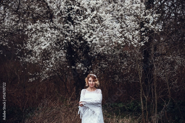 Fototapeta Young beautiful blonde woman in blooming garden. Bride.