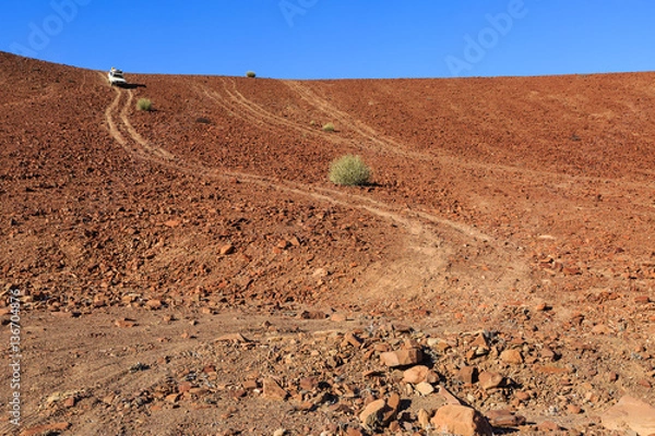 Fototapeta Geländewagen fährt steinigen Hügel hinunter, Damaraland, Kunene Region