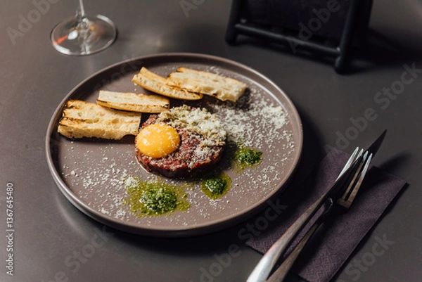 Fototapeta Ostrich tartare with a rich Italian touch. Finely chopped ostrich meat served with egg yolk, capers, artichokes, cornichons, and Mars onion. Paired perfectly with signature toasted bread