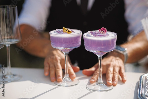 Obraz A bartender is preparing two vibrant purple cocktails on a table