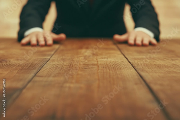 Fototapeta businessman sitting at wooden table with hands visible creating perspective view of rustic conference surface with focus on grain texture