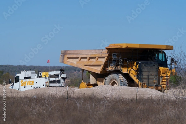 Obraz Very large dump truck is getting a tire change from a mobile service truck on-site at a rock quarry in West Texas.