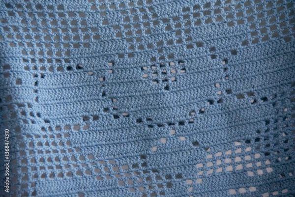 Fototapeta A beautiful pattern knitted from blue wool yarn using the fillet knitting technique
