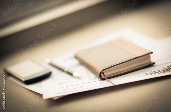 Fototapeta personal organizer and pen lie on documents on the desktop