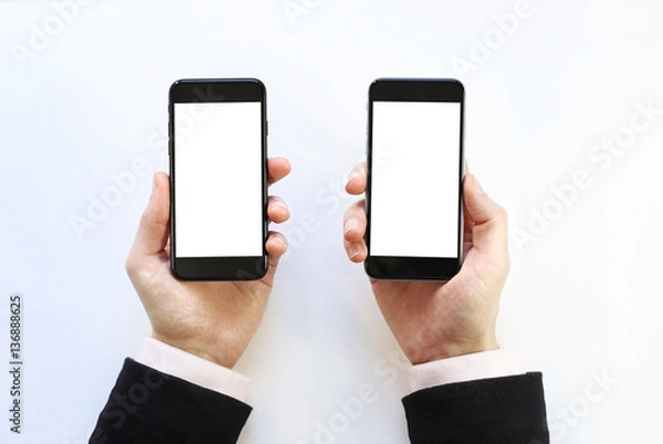 Fototapeta  two smartphones in the hands. on a white background 