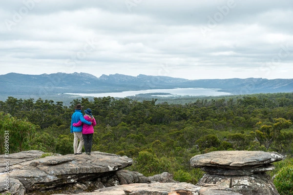 Obraz Couple looking at Stunning Grampians National Park View. Older couple standing arm in arm looking at eucalyptus forest and distant lake.