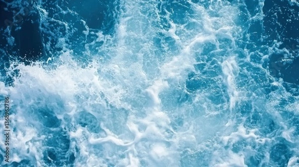 Fototapeta Aerial view of churning blue water with white foam and wave patterns.