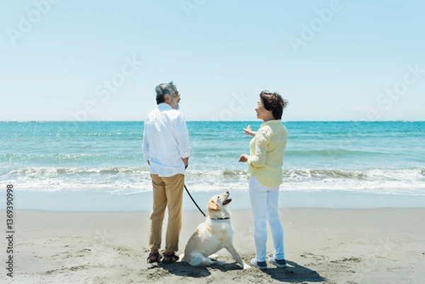 Obraz 愛犬を連れて浜辺を散歩するシニア夫婦