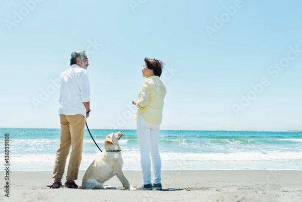 Obraz 愛犬を連れて浜辺を散歩するシニア夫婦