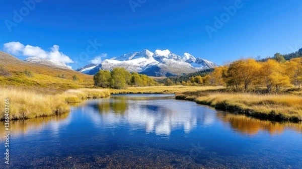 Fototapeta Serene alpine lake reflecting autumnal peaks.  Tranquil mountain landscape with a crystal-clear lake mirroring the fall colors of the surrounding trees and the snowy mountain peaks in the distance.  