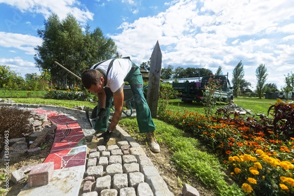 Obraz Rzemieślnik układa kostkę brukową w ogrodzie
