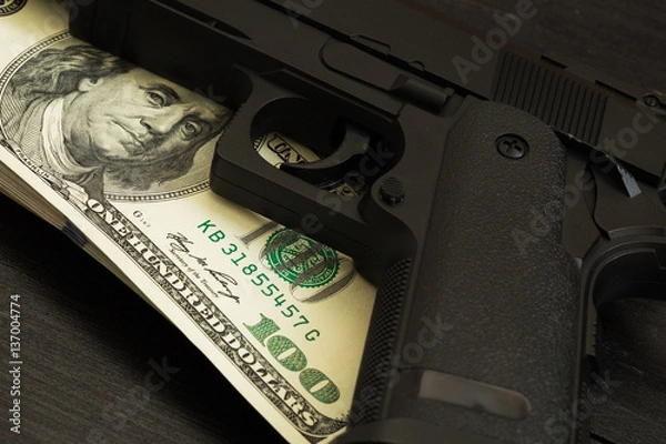 Fototapeta trigger gun on banknotes. concept of illegal arms trafficking and criminal offenses