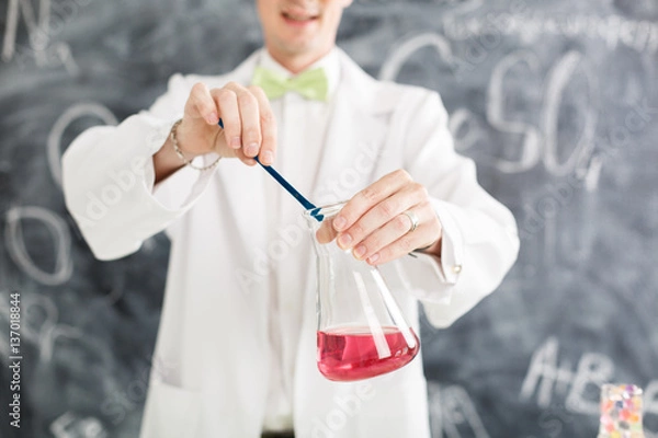 Fototapeta Chemist carries chemistry experiment in laboratory. Test-tubes with chemical reagent. Chemical Laboratory. Chemistry lesson. Study chemistry. Scientist at laboratory. Professor. Yellow glasses