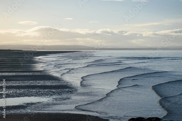 Obraz Serene Aberlady Bay in East Lothian, Scotland, showcasing gentle winter waves cascading across wet sand at low tide, bordered by soft cloudy skies on a tranquil coastal morning - Seton Sands, UK