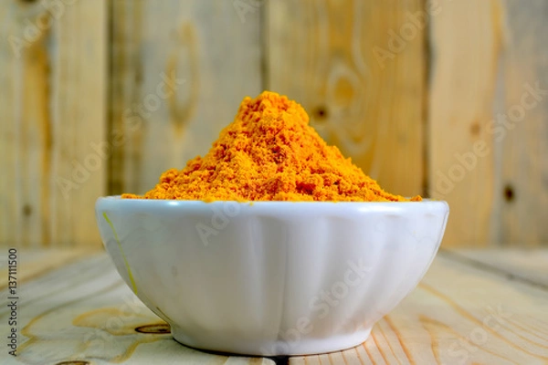 Obraz Tumeric powder in a bowl isolate on wooden background