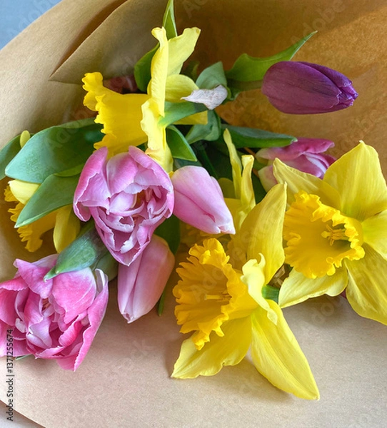 Fototapeta Перейти к странице
|12345...11Далее
Beautiful composition of the first spring flowers with green leaves in a bouquet. Yellow daffodils, pink tulips in a bouquet on craft paper, top view.