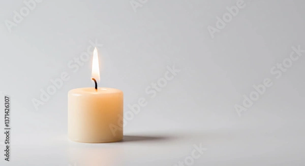 Fototapeta  single candle burning softly in the center of a plain white background