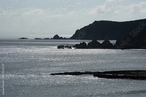 Fototapeta Backlit, and silhouetted headlands jutting out into the Pacific Ocean at Tawharanui Regional Park, Auckland, New Zealand.