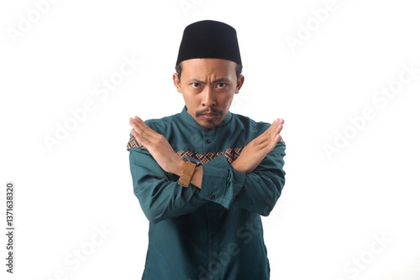 Fototapeta Asian Muslim man crossing his arms in an "X" gesture, signaling prohibition or restriction. His firm expression emphasizes avoiding actions that break Ramadan fasting. Isolated on a white background