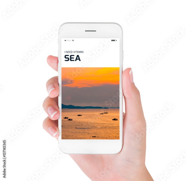 Fototapeta Woman hand shows aerial view of the sea at sunrise on smartphone display isolated on white background