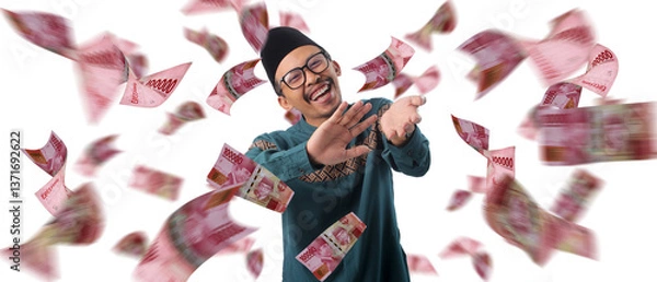 Fototapeta Indonesian Muslim man making a money gesture with his hands, surrounded by floating one hundred Rupiah bills, isolated on a white background.
