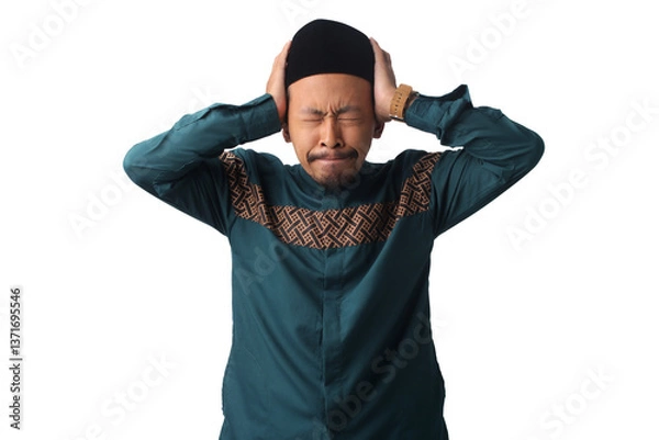 Fototapeta Stressed Asian Muslim man with eyes closed, holding his head, struggling to control his emotions and resist temptations while fasting during Ramadan, isolated on a white background