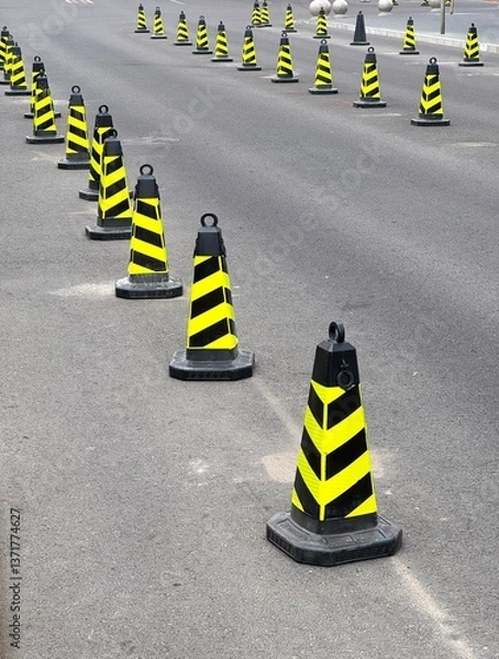 Obraz Safety Cones in a row. Rows of black and yellow safety cones on asphalt.