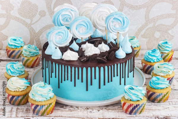 Obraz Children's blue cake and cupcakes rainbow color on a white background with meringue