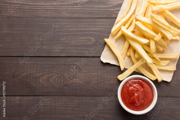 Obraz French fries with ketchup on wooden background