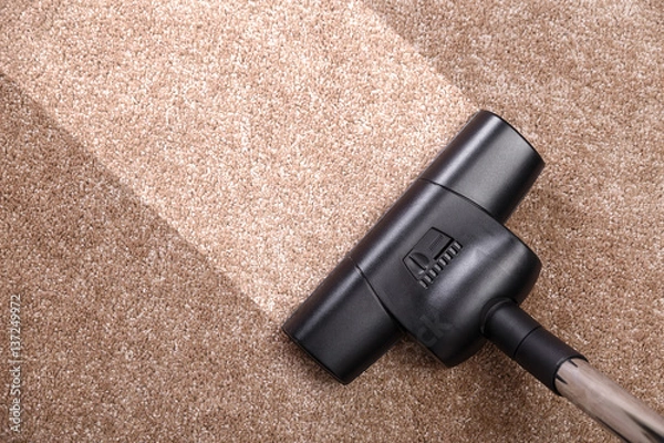 Fototapeta Vacuuming carpet with vacuum cleaner. Housework service. Close up of the head of a sweeper cleaning device.