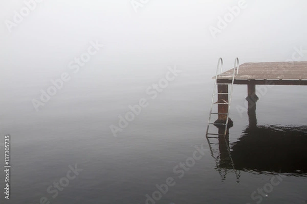 Obraz A wooden pier and stairs to sea in a foggy day.