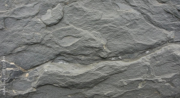 Fototapeta A rugged, timeless gray stone texture, showcasing the raw beauty of nature's artistry with deep shadows and subtle light variations.