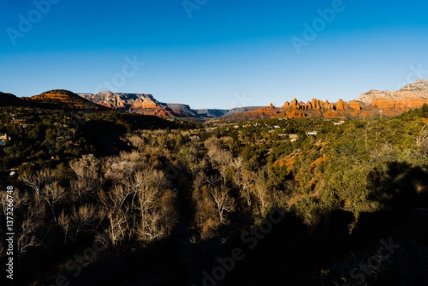Obraz sun hitting red rocks in the background with trees and houses in foreground
