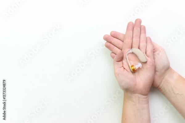 Fototapeta Woman holding a hearing impairment device in the hands with a white background and copy space in the left side 