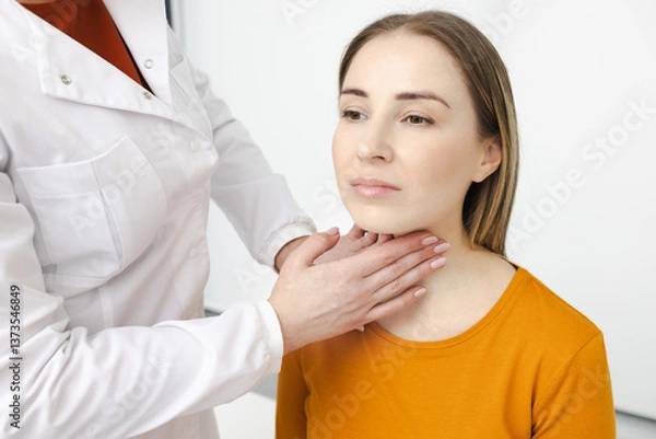 Fototapeta Doctor palpates of woman's neck for diagnostics of thyroid diseases and hypothyroidism at medical clinic. Thyroid treatment