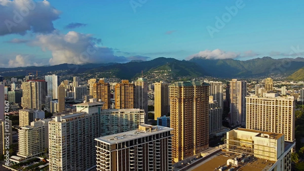 Fototapeta Aerial view of Honolulu high-rise buildings and lush mountains.
