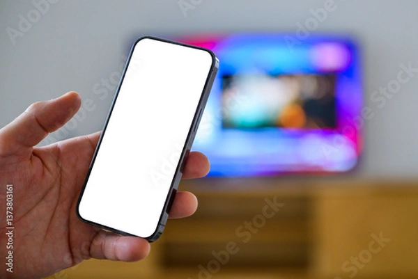 Obraz Smartphone mockup screen, man holding mobile phone in front of television set, tv remote app and tv program listing concept