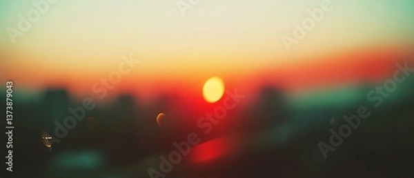 Fototapeta A radiant sun dominates the blurry city backdrop, casting warm, vibrant hues into a deeply soothing sunset tableau.