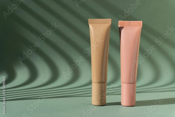 Obraz Natural foundation cream tubes mockup. Brown and pink lotion containers on green background with Light on wall.