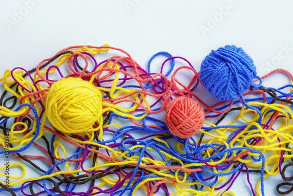 Fototapeta Untangling tangled threads. Multicolored tangled threads and  attempt to wind them into balls. White background, flat lay, copy space