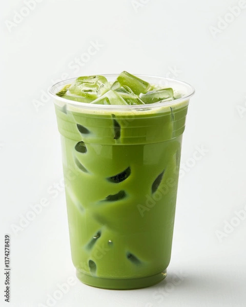 Fototapeta refreshing iced matcha latte in clear plastic cup against plain background