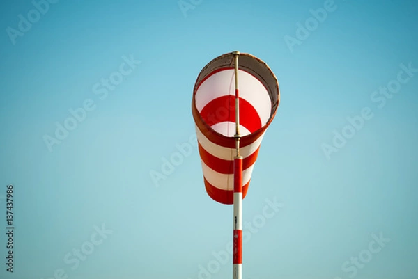Fototapeta Horizontally flying windsock (wind vane) due to high wind. Blue sky in the background. Success concept.