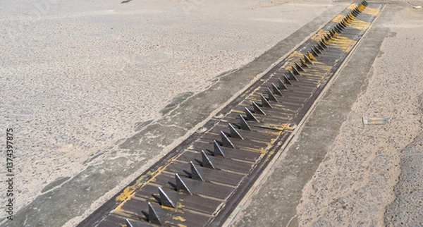Fototapeta metal spikes in the asphalt, tire spike strip, spike barrier, one-way traffic spike, tire killer