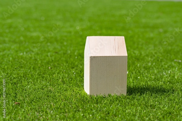 Fototapeta Small wooden model house isolated on the lush green grass of a lawn. Housebuilding and home ownership concept. Copy space.