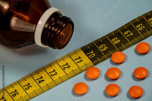 Obraz orange medicine pills with measuring tape and bottle. Weight loss idea