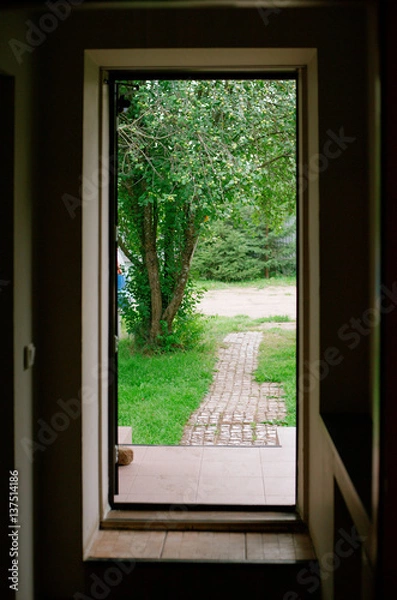 Fototapeta open the door to the old park, paving stones, the trail to the green trees in the summer, view from the house