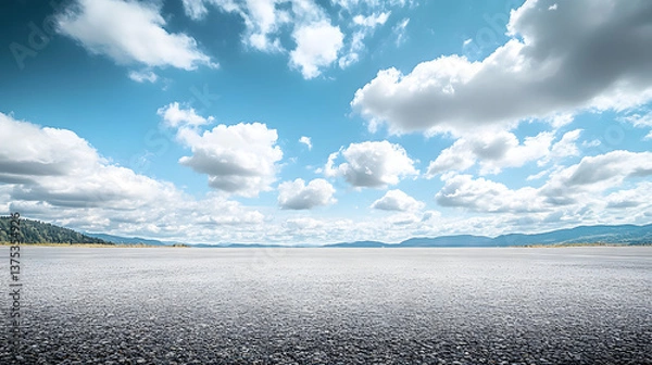Fototapeta Head up shot, the middle scene is a wide cement ground with a small amount of gravel and sand on the ground, and in the distance is a vast sky with white clouds. The overall picture style is very fres