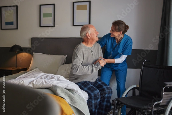 Fototapeta Smiling nurse assisting disabled senior man to get up from bed